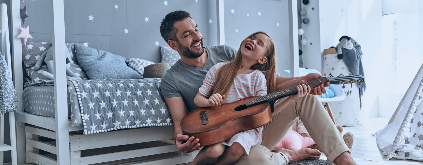 Father and daughter holding a guitar together.