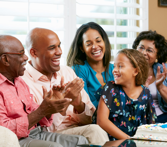 Family smiling and celebrating a young girl's birthday.