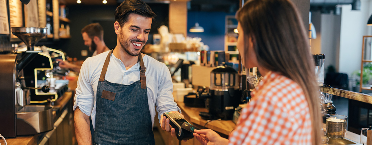 Image of a woman using tap to pay with her MY Card at a coffee shop