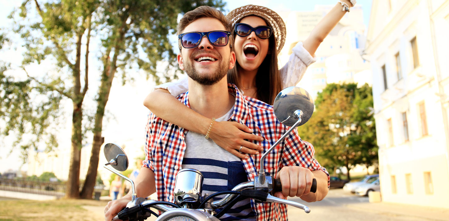 Two people having fun riding on a motor scooter.