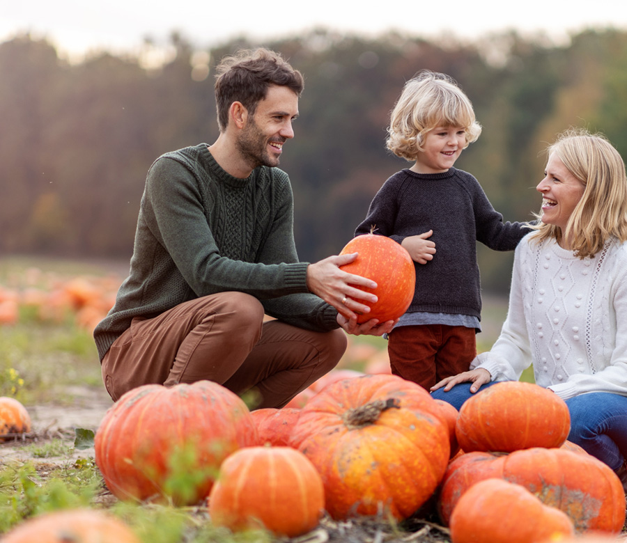 Family in a pumpkin patch together.