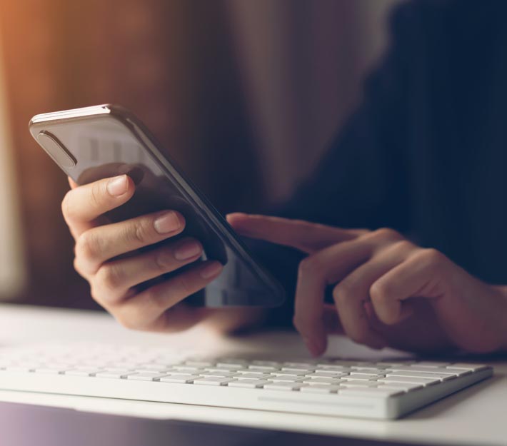 Woman's hands use a phone at a computer keyboard