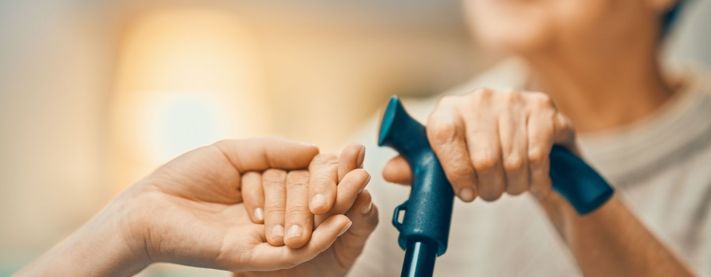 Individual holding hands of elderly person.