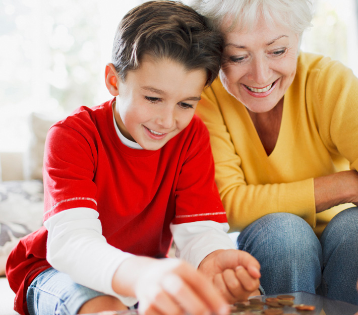 Smiling little boy and grandma count loose change together.