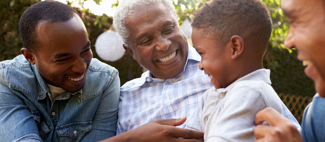 A grandfather smiles with his son and grandson